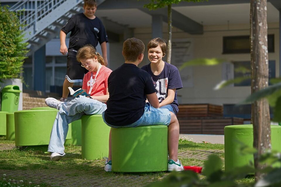 Schüler sitzen in der Pause auf Sitzgelegenheiten und unterhalten sich